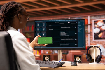 Poster - Woman using isolated screen smartphone and AI LLM chatbot on computer screen in home office. Person holding chroma key phone uses artificial intelligence chatbot on monitor