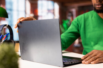 Poster - Freelancer sitting at desk in home office using laptop, close up. Teleworker in apartment working on notebook, composing and sending files online in order to finish tasks