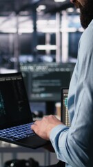 Fototapete - Vertical video Close up of developer in data center coding with generative AI assistance on laptop. IT expert leveraging artificial intelligence large language model on notebook to solve tasks, camera