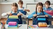 © MUHAMMADADIALFARIS - Four elementary school children sitting at desks in a classroom, packing or unpacking books and supplies into their backpacks.