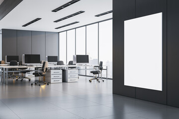 Poster - Modern open office interior with bright lighting, clean desks, large windows, and vertical blank poster mockup on dark wall surface. 3D Rendering