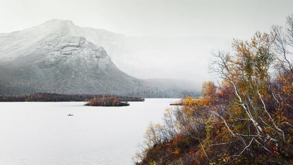 First snowfall in the Khibiny Mountains with yellow autumn trees and snow capped mountains. Russia.