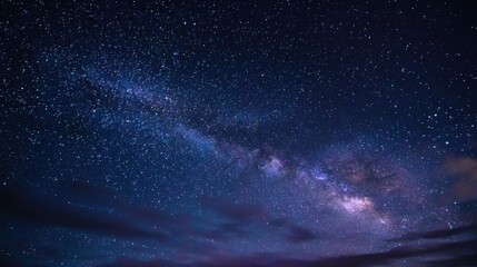 Wall Mural - A breathtaking view of countless twinkling stars fills the night sky, showcasing the milky way's stunning band of light over a tranquil landscape with gentle clouds.