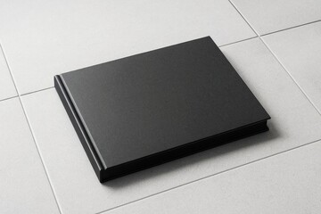 Poster - Black hardcover book mockup placed on light tiled surface with clean layout suitable for branding, poster or promotion design concept template.