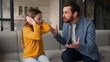 © Yuliia - Annoyed Caucasian man dad male screaming shout on little kid disobedience scold child offended naughty daughter girl ignore avoid angry father closing ears with hands at home family conflict argument