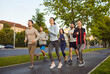 © Studio Romantic - Outdoor shot of active young people running together along road, dressed in sportswear, having morning workout, having sporty lifestyle. Group of friends having sport training in open air