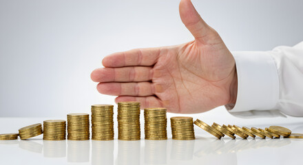 Poster - Hand Protects Gold Coins Stack from Domino Effect in Financial Risk Business Crisis Concept on a Reflective White Background