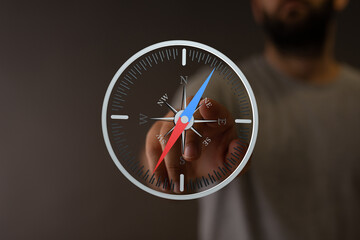 Poster - A man's finger interacts with a digital compass interface, illustrating guidance and direction.