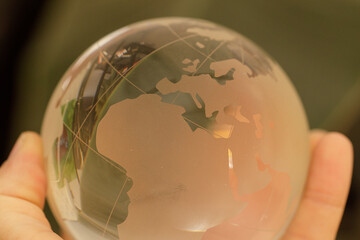 Poster - Close-up of a hand holding a glass globe, showcasing a detailed world map. Perfect for global concepts.