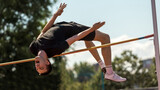 An athlete leaps impressively through the air at a high jump event in an open-air competition. Concept of movement study, biomechanics, sports science, physical capability