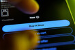 © Rokas - Closeup of a finger tapping the Buy It Now button on a smartphone screen during online shopping.