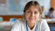 © Anastasiia - Young woman with name badge sitting in classroom environment.
