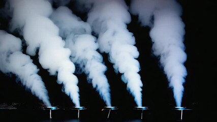 Poster - Smoke machines create vertical columns of smoke rising from vents in a stage floor, illuminated with blue light against a black background, suggesting a mysterious or suspenseful atmosphere