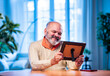 © StockImageFactory - Elderly Indian man holding framed photo with love, lost in memory and emotion