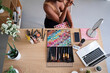 © Studio Marmellata - From above of unrecognizable crop black female sitting at table and doing makeup while looking in mirror at home and watching online video lesson on laptop