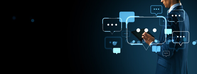 Poster - Businessman using tablet with digital chat bubbles representing online communication and social media interaction on dark background.