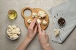 © New Africa - Woman cutting raw cauliflower at light table, top view