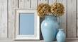 © GL Designs - Rustic White Picture Frame with Blue Mat and Dried Hydrangeas in Blue Vases Against Shabby Chic Wooden Wall