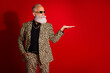 © deagreez - Fashionable elderly man in leopard suit making gesture on bold red backdrop showcasing eclectic fashion and jubilant persona