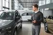 © Serhii - Portrait of Modern car seller standing in car salon with copy space