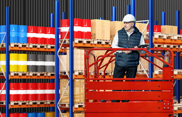 Poster - Man warehouse auditor. Supervisor recounts goods in storage area. Auditor inside warehouse hangar. Man manager in distribution center with barrels and boxes. Warehouse auditor in basket with lift