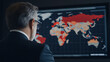 © photo for everything - Analyzing Global Trends: A man studies a world map displaying varied data points, indicating areas of focus or concern, set against a dark background.