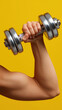© OleksandrZastrozhnov - Close-up of strong arm lifting dumbbell against yellow background