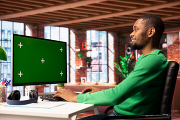Poster - Cheerful man at home using green screen computer monitor to browse social media website, looking at memes. Smiling person in apartment looking at funny content online on chroma key PC display