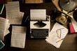 © pressmaster - Vintage typewriter sitting on wooden desk surrounded by scattered typed manuscript pages, rotary telephone, eyeglasses, pen, and books, evoking classic writing workspace