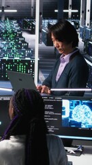 Poster - Vertical video Software developers cooperating in data center, reviewing AI diagnostics on computer. IT staff members discussing in server room, optimizing machine learning systems, camera A
