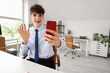 © Pixel-Shot - Young businessman video chatting with mobile phone at table in office