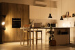 © Pixel-Shot - Interior of modern kitchen with counters, table and glowing lamps at night