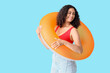 © Pixel-Shot - Young African-American woman with orange inflatable ring on blue background