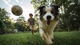 A boy runs with his dog in a grassy yard as a soccer ball flies through the air on a sunny day. They are playing together cheerfully.