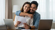 © Fauzan - Happy couple, paperwork and hug with laptop for budget, paying bills or estate planning. Married people, embrace and documents for insurance policy, investing and savings in apartment or family home