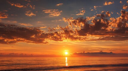Wall Mural - A stunning sunset illuminates the sky with vibrant oranges and yellows. The tranquil ocean reflects the colors while fluffy clouds create a beautiful backdrop. Perfect serenity at dusk.