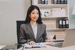 © ARMMY PICCA - Portrait of Young Asian woman hand freelancer is working her job on computer tablet in modern office. Doing accounting analysis report real estate investment data, Financial and tax systems concept.