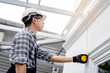 © Summer Paradive - Asian male construction worker in protective workwear using tape measure on the wall. Home builder man checking the length of house wall. Measuring tool for building measurement and inspection