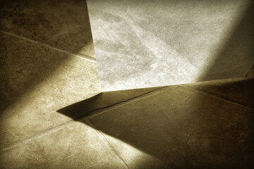 Aufkleber - Thin canvas sheet folded in sharp angles, casting dramatic shadow on textured stone tile floor, warm lighting creates abstract, minimalist, artistic mood