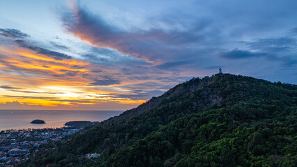 Wall Mural - A breathtaking aerial view of the iconic Big Buddha statue overlooking the Andaman Sea in Phuket, Thailand, captured during a vibrant sunset. The golden sky reflects on the water. beautiful sunset