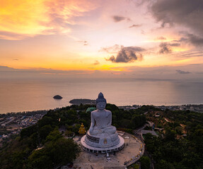 Wall Mural - A breathtaking aerial view of the iconic Big Buddha statue overlooking the Andaman Sea in Phuket, Thailand, captured during a vibrant sunset. The golden sky reflects on the water, majestic hilltop
