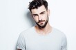 © Supanat - Attractive young man with styled dark hair and beard wearing casual gray t-shirt posing against plain white background.