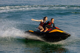 Happy couple riding a jet ski on water. Concept of joy, entertainment and summer adventure.