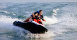 Happy couple riding a jet ski on water. Concept of joy, entertainment and summer adventure.