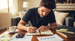 © Ali - A man writing in a notebook at a table in a living room with coffee cup