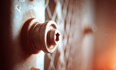 Poster - Rusty bolt on a metal gate with warm sunlight illuminating the texture in an industrial setting