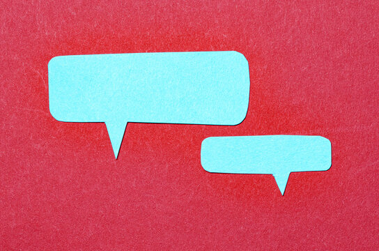 Blue blank cut out paper speech bubbles with copy space for text on red background, flat lay top view conceptual conversation backdrop