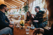 © qunica.com - A group of young friends enjoying a lively conversation and coffee together in a beautifully decorated cafe. The environment exudes warmth and happiness, emphasizing bond and shared moments.