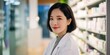 © Seksan - Smiling woman in a lab coat stands confidently in a pharmacy, surrounded by shelves of products.