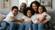© Dual Studio - Portrait of happy mature couple with son and daughter relaxing on sofa at home. Middle aged black woman with husband and children smiling and looking at camera. Beautiful mid african american family.